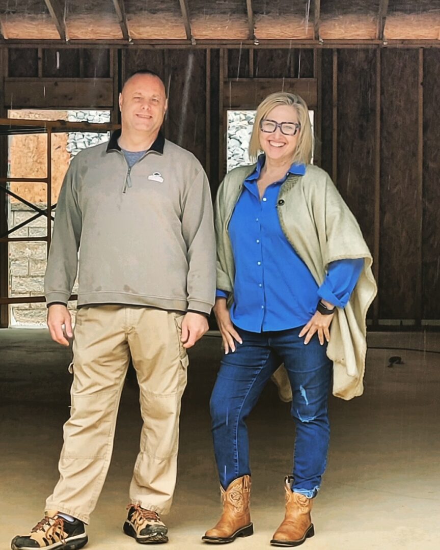 A man and woman standing in front of a barn.