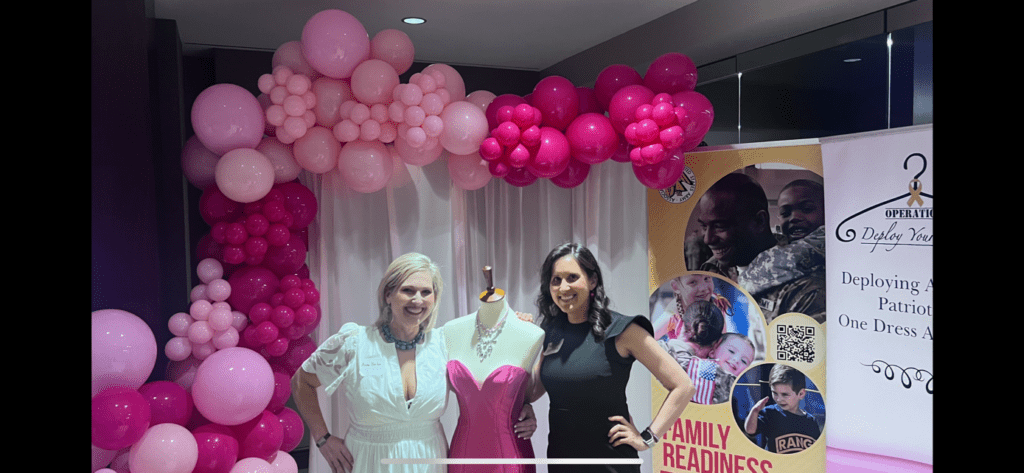 Two women posing for a picture in front of balloons.