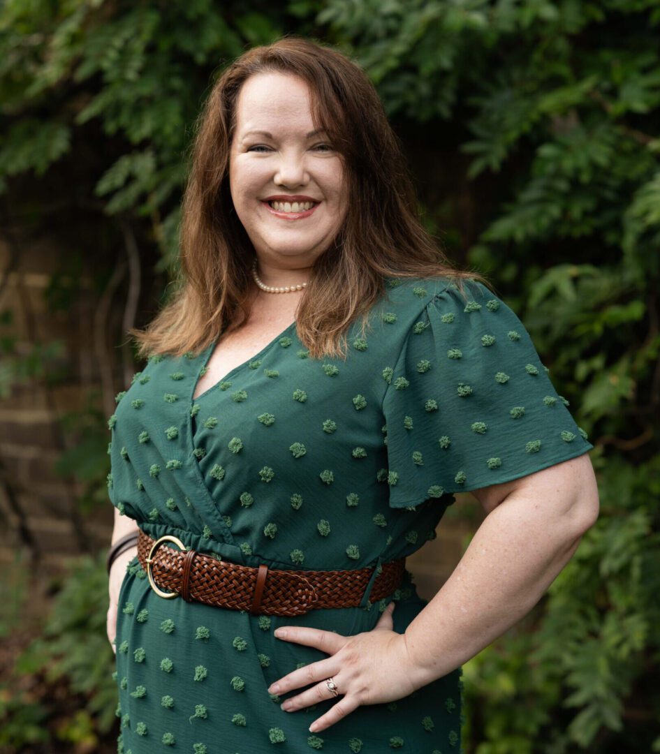 A woman in green dress standing next to tree.