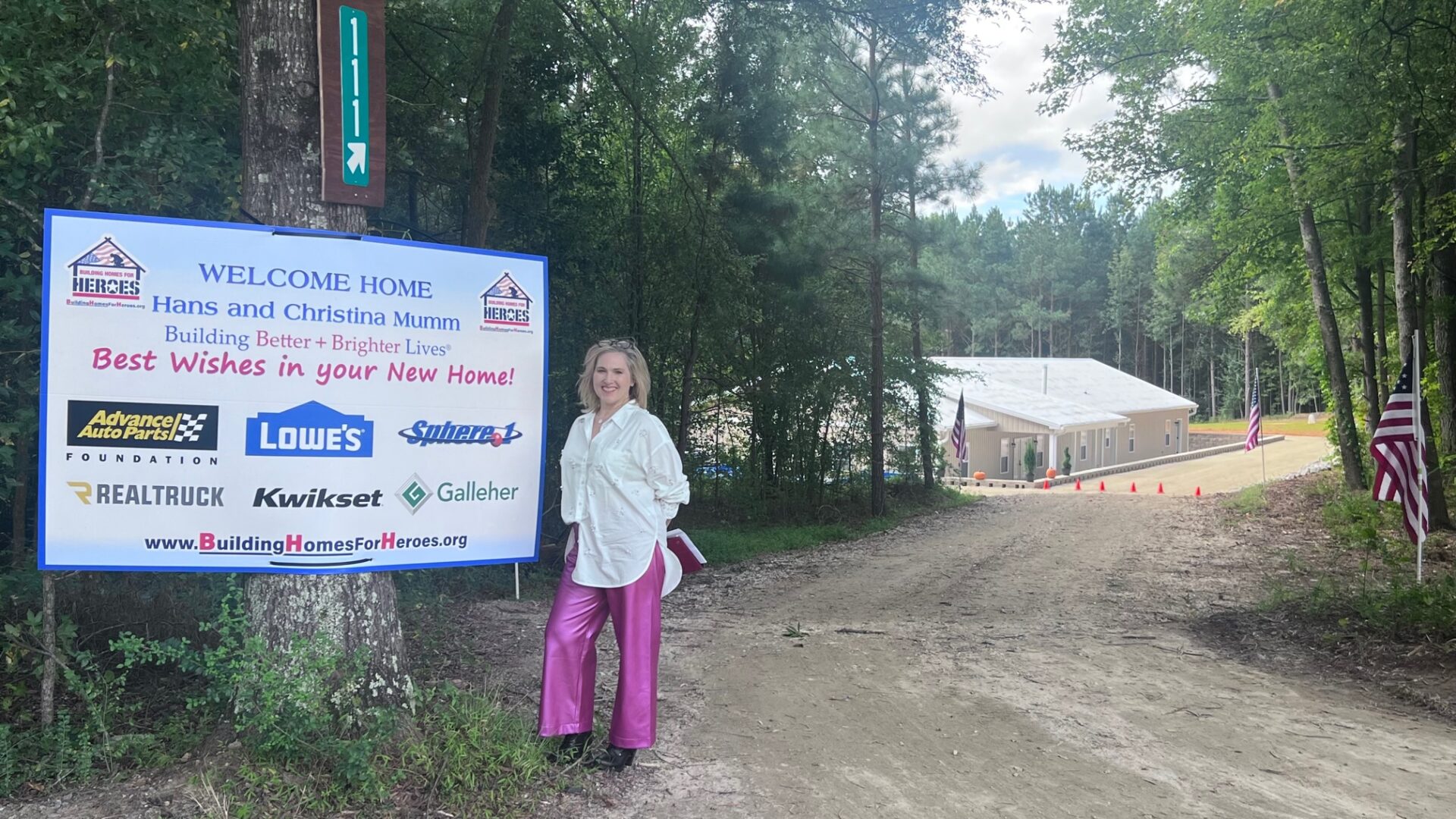 A woman standing next to a sign on the side of a road.