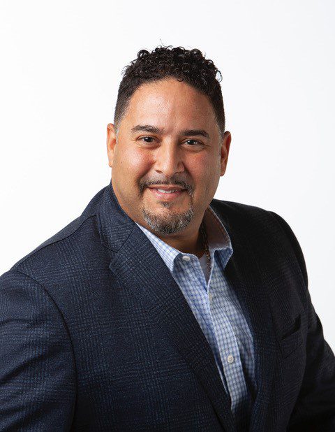 A man in a suit and tie smiling for the camera.