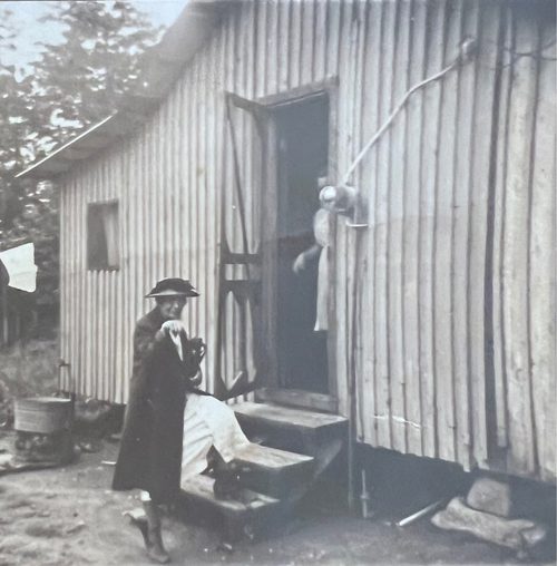 A woman in front of a wooden house.